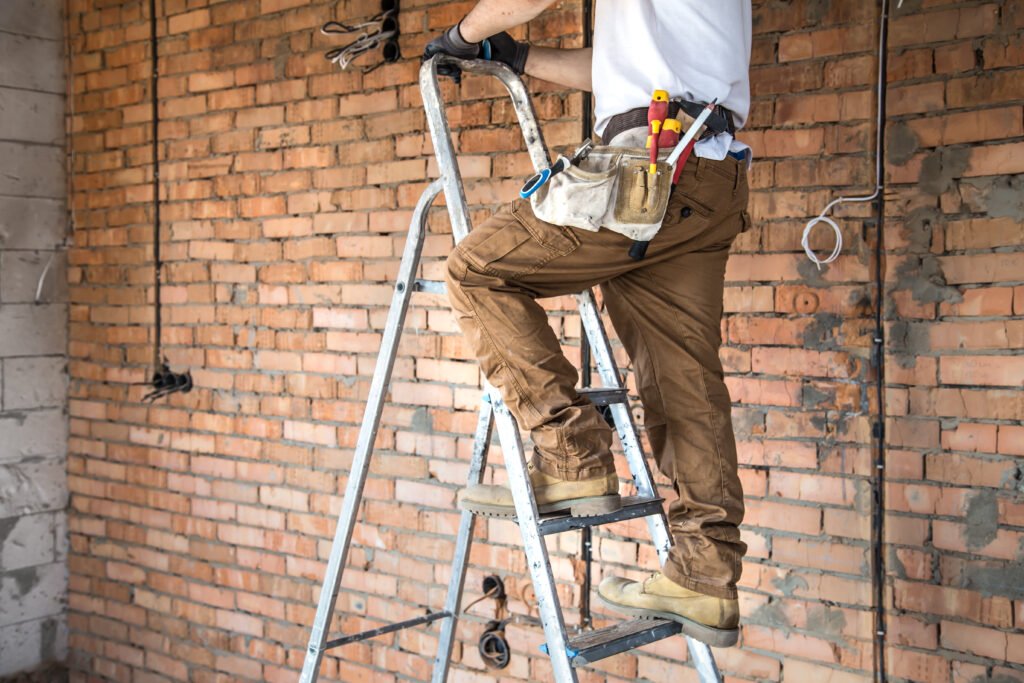 Electrician with tools, working on a construction site. Repair and handyman concept. House and house reconstruction.